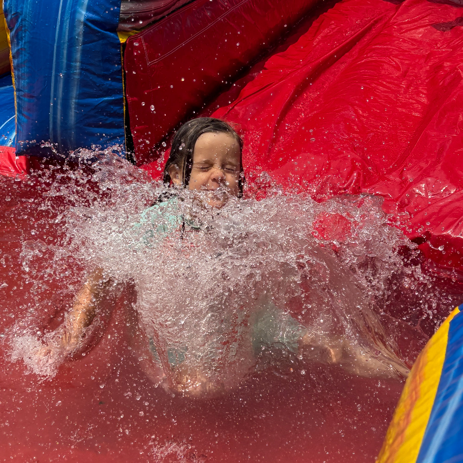 A child spashing down a waterslide during our Spring Picnic.
